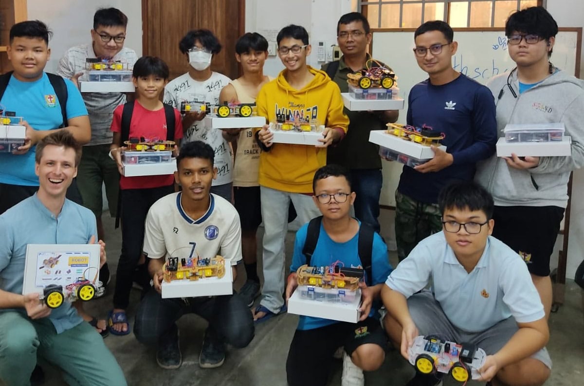 Cambodia robotics programme participants and mentors holding the robots they built.